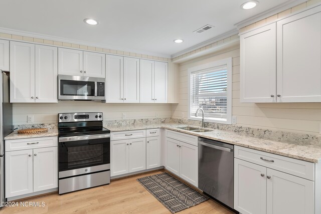 kitchen with appliances with stainless steel finishes, white cabinetry, light hardwood / wood-style flooring, and sink