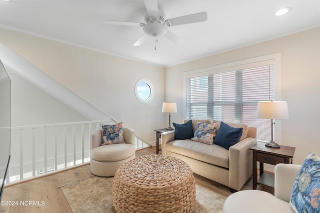 living area with wood finished floors, a ceiling fan, and crown molding