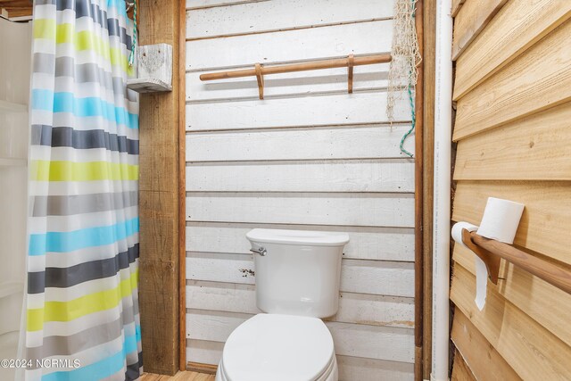 bathroom with toilet and wood walls