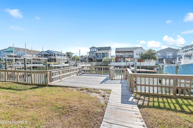 view of dock with a residential view, a yard, and boat lift