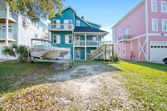 rear view of house featuring a balcony, a yard, and a garage