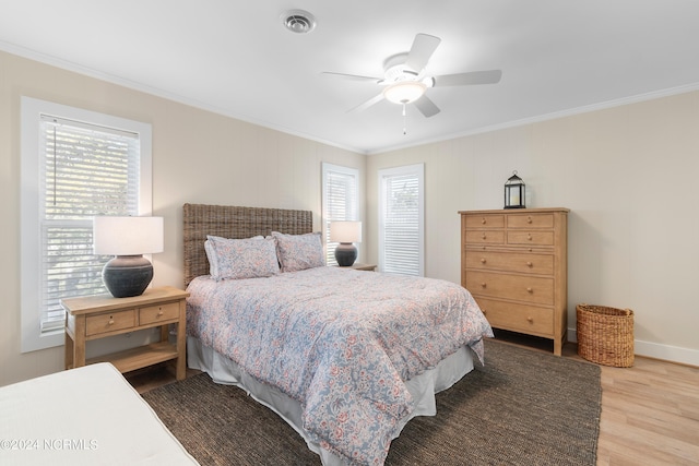 bedroom with ceiling fan, ornamental molding, wood-type flooring, and multiple windows