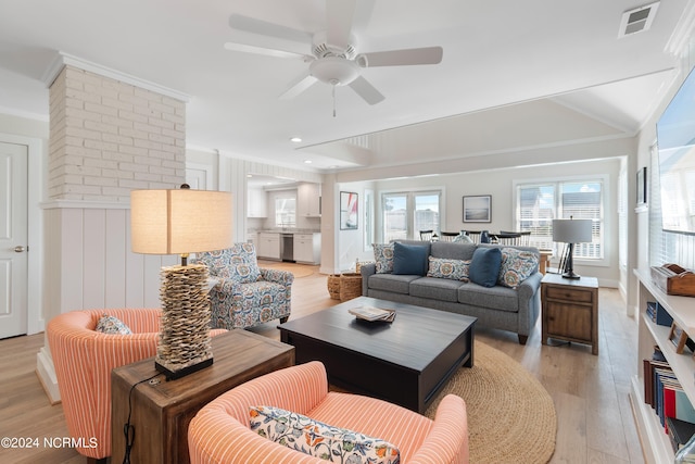 living room with a ceiling fan, visible vents, crown molding, and light wood finished floors