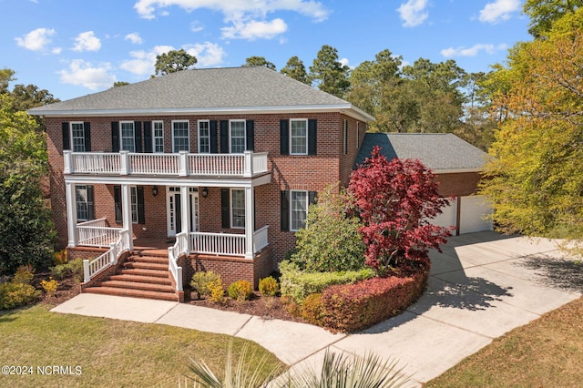 view of front facade featuring a balcony, a front yard, a porch, and a garage