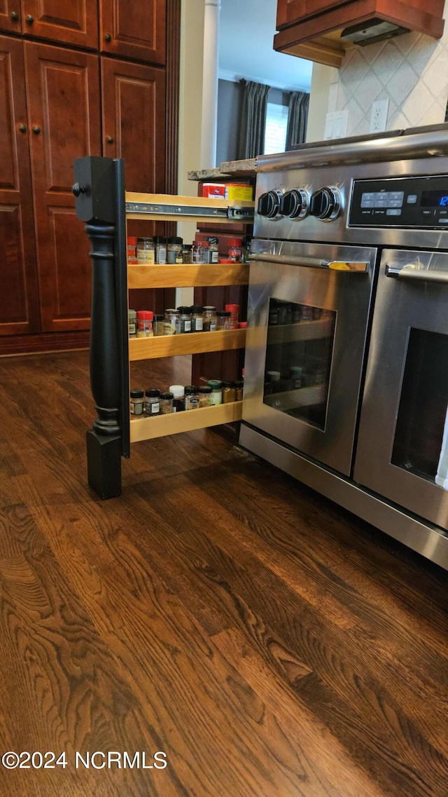 kitchen with high end stove, backsplash, and dark wood-type flooring