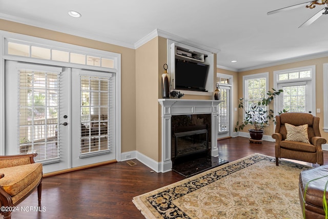 living room with ceiling fan, a premium fireplace, dark wood-type flooring, and crown molding