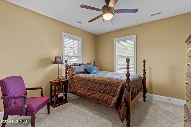 bedroom with ceiling fan, light carpet, and multiple windows