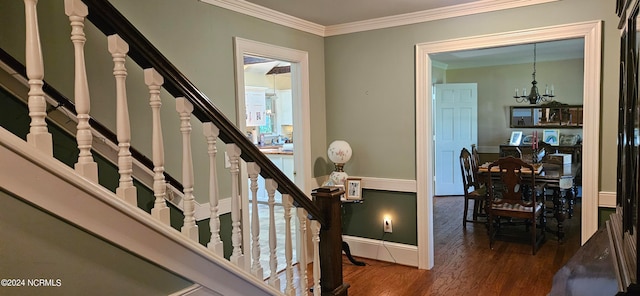 staircase featuring crown molding, an inviting chandelier, and dark hardwood / wood-style flooring