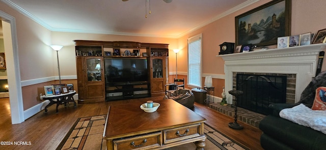 living room featuring ceiling fan, crown molding, a fireplace, and dark wood-type flooring