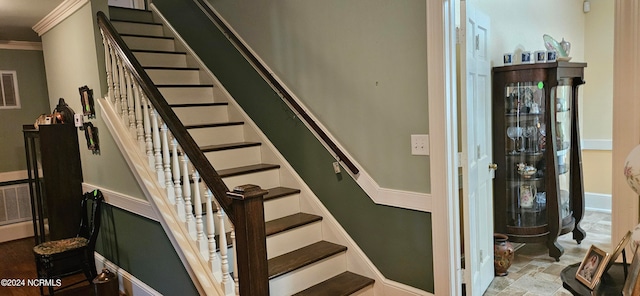 staircase with light tile floors and ornamental molding