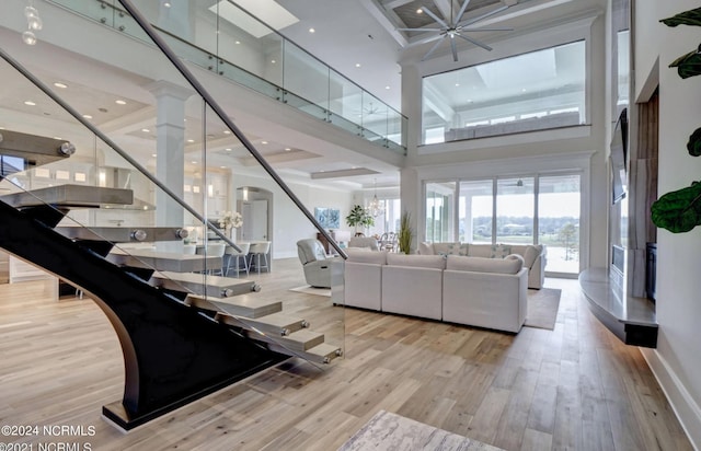 unfurnished living room featuring light hardwood / wood-style flooring, a towering ceiling, and decorative columns