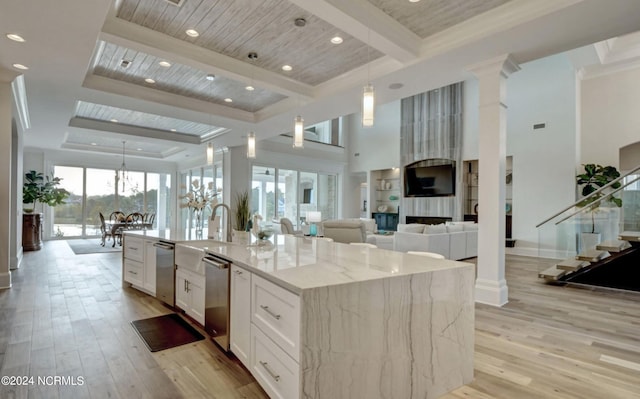 kitchen with a kitchen island with sink, decorative light fixtures, white cabinetry, light stone counters, and wood ceiling