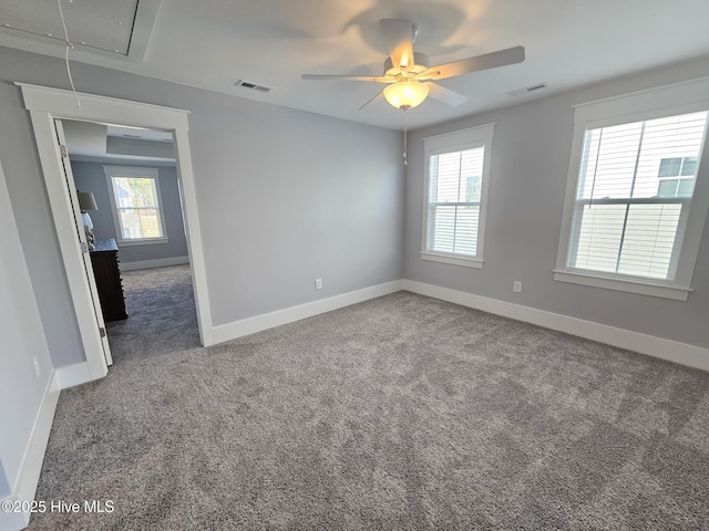 carpeted spare room featuring attic access, baseboards, and visible vents