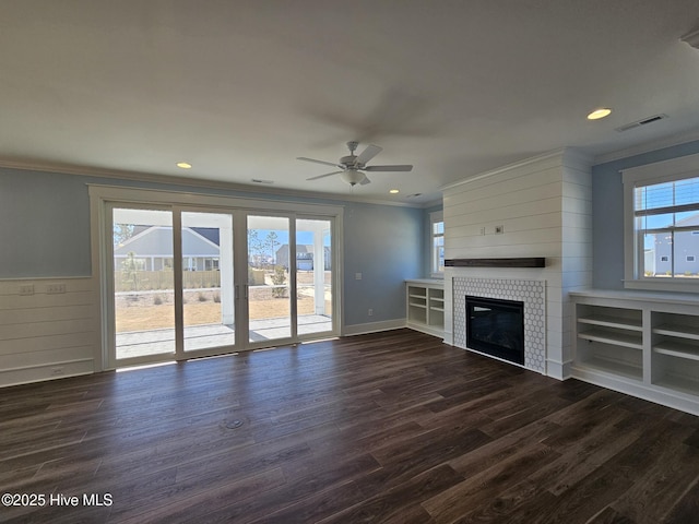 unfurnished living room with ornamental molding, plenty of natural light, dark wood-type flooring, and a fireplace