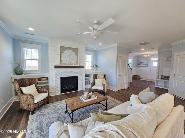 living room featuring a tiled fireplace, crown molding, and plenty of natural light