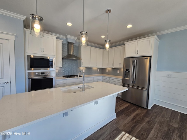 kitchen featuring sink, decorative light fixtures, wall chimney range hood, stainless steel appliances, and white cabinets