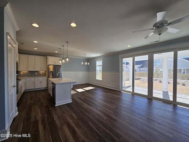 kitchen featuring ornamental molding, a kitchen island with sink, dark hardwood / wood-style floors, and decorative light fixtures