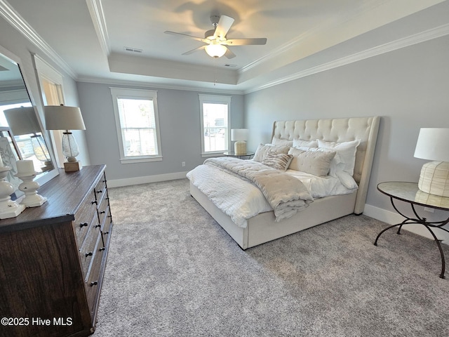 carpeted bedroom with visible vents, crown molding, a raised ceiling, and baseboards