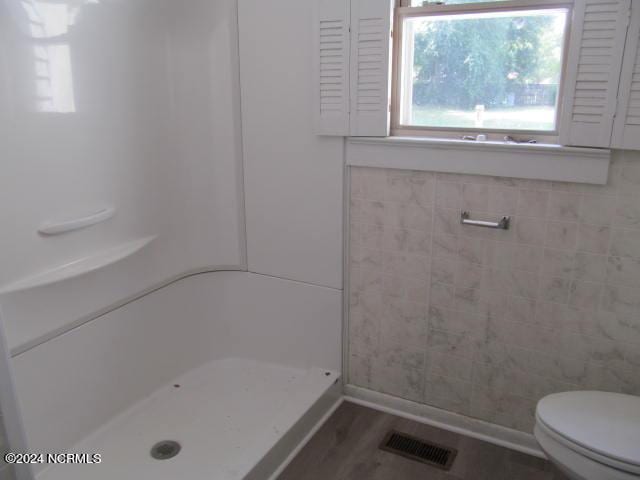 full bathroom featuring visible vents, toilet, wood finished floors, tile walls, and a shower