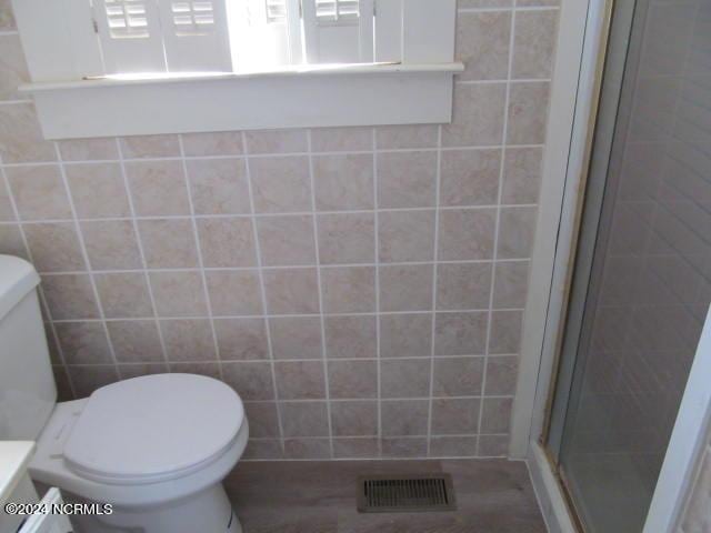 full bathroom featuring visible vents, a stall shower, toilet, and tile walls