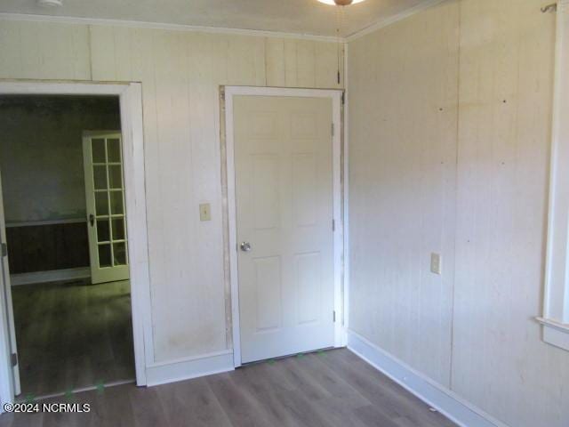 unfurnished bedroom featuring a closet, wood finished floors, baseboards, and ornamental molding