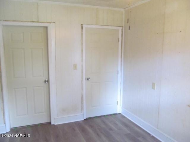 unfurnished bedroom featuring baseboards, wood finished floors, and crown molding