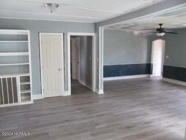 empty room with visible vents, wood finished floors, arched walkways, and ceiling fan