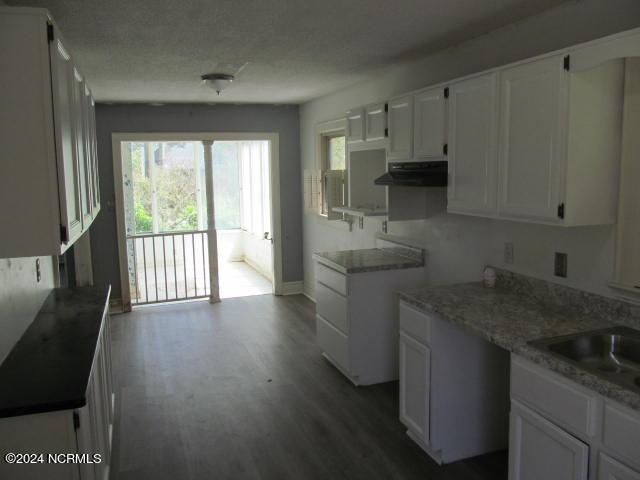 kitchen with a textured ceiling, sink, hardwood / wood-style floors, and white cabinets