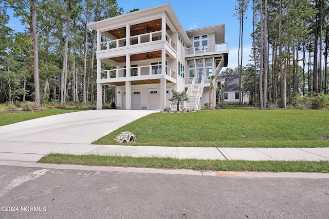 view of front of home with ceiling fan, a garage, a balcony, and a front lawn