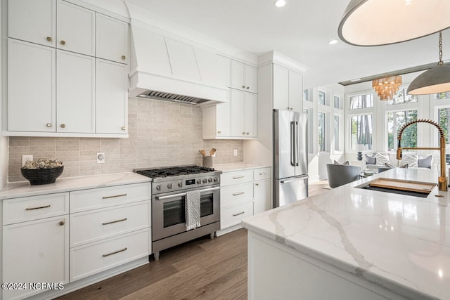 kitchen featuring premium appliances, pendant lighting, dark wood-type flooring, white cabinets, and premium range hood