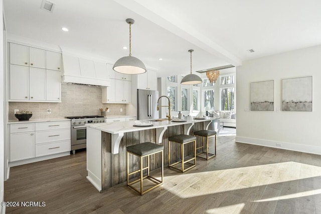 kitchen with white cabinetry, hanging light fixtures, high end appliances, a center island with sink, and custom exhaust hood