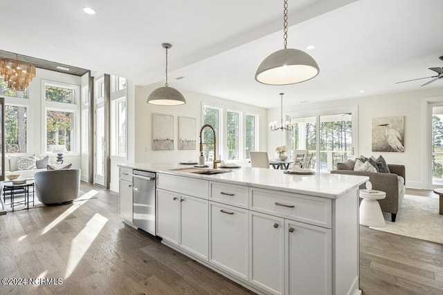 kitchen featuring a kitchen island with sink, hanging light fixtures, sink, and a chandelier