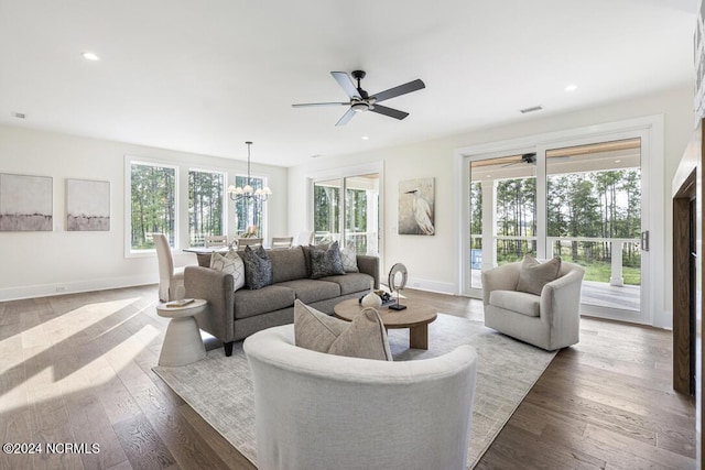 living room with a healthy amount of sunlight, dark hardwood / wood-style floors, and ceiling fan with notable chandelier