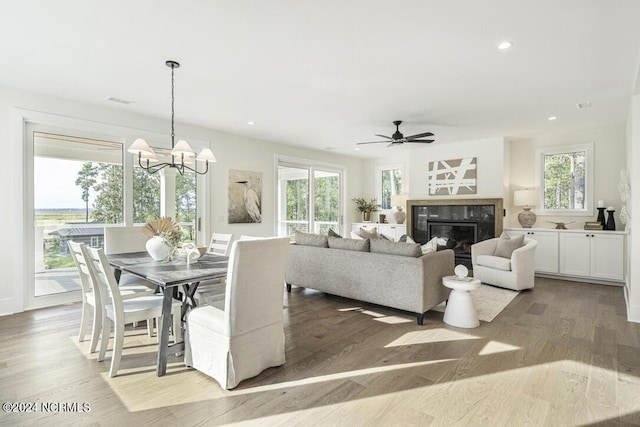 living room featuring a high end fireplace, light hardwood / wood-style flooring, and ceiling fan with notable chandelier