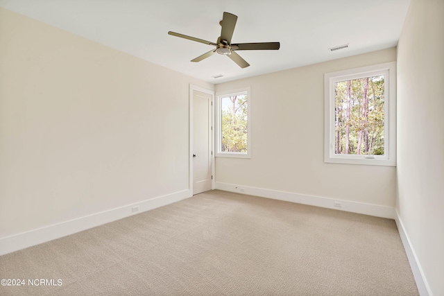 carpeted spare room featuring a healthy amount of sunlight and ceiling fan