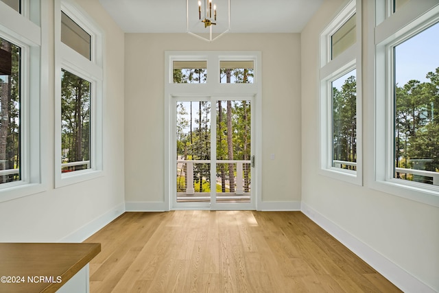 unfurnished sunroom featuring a healthy amount of sunlight and a chandelier