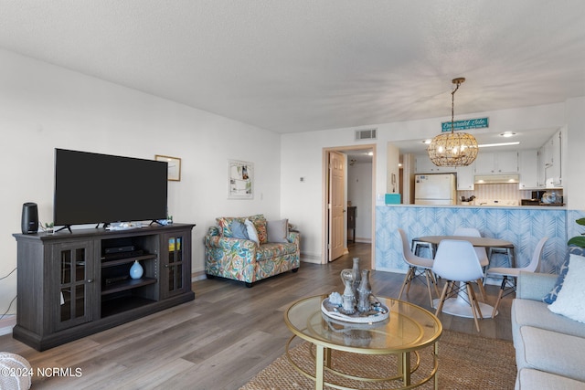 living room featuring a chandelier, a textured ceiling, and hardwood / wood-style flooring