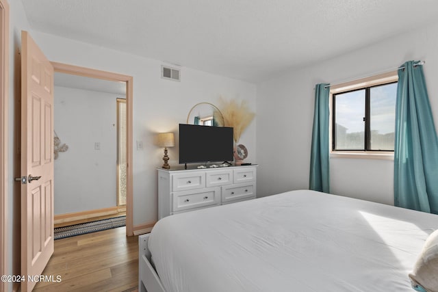 bedroom with a textured ceiling and light wood-type flooring