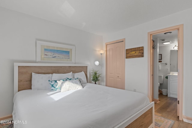 bedroom featuring a closet, ensuite bathroom, and light hardwood / wood-style flooring