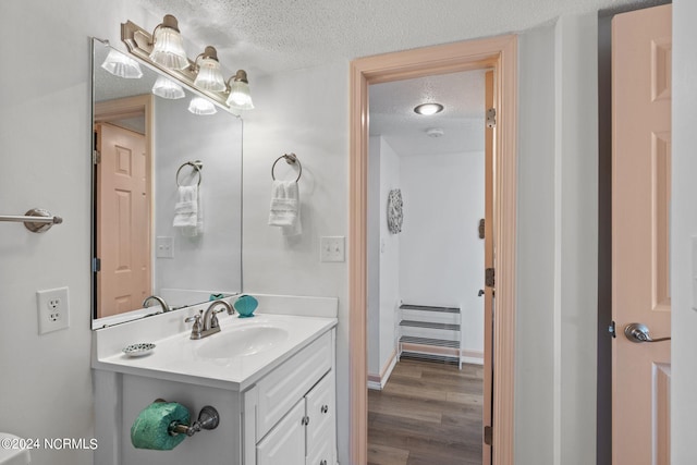 bathroom with hardwood / wood-style floors, vanity, and a textured ceiling