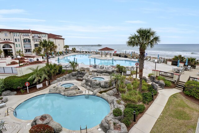 view of swimming pool featuring a community hot tub and a water view