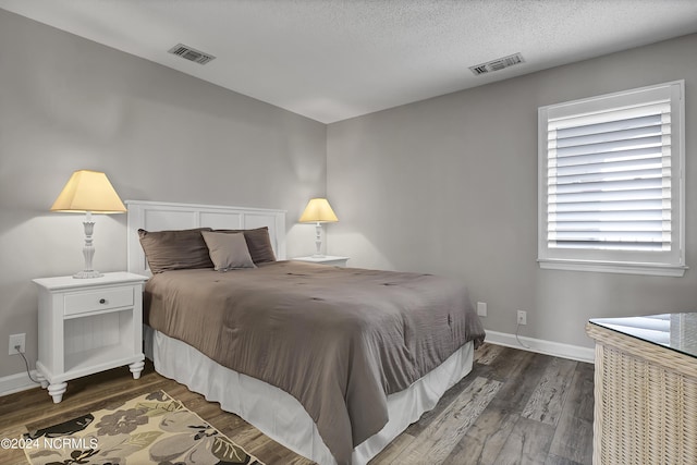 bedroom with dark hardwood / wood-style floors and a textured ceiling