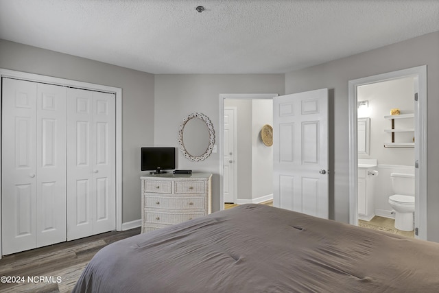 bedroom with connected bathroom, a closet, dark hardwood / wood-style floors, and a textured ceiling