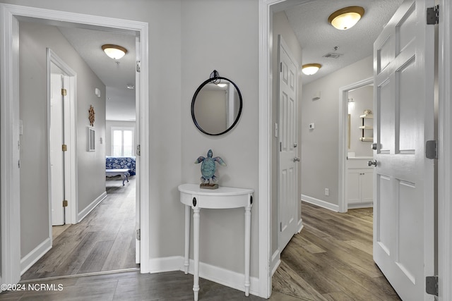 corridor with wood-type flooring and a textured ceiling