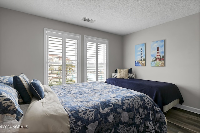 bedroom featuring multiple windows, a textured ceiling, and dark hardwood / wood-style flooring