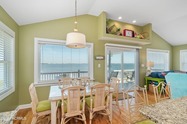 dining room featuring a water view, vaulted ceiling, and light wood-type flooring