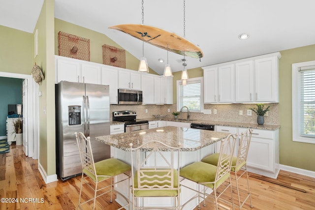 kitchen with stainless steel appliances, lofted ceiling, a center island, and white cabinets