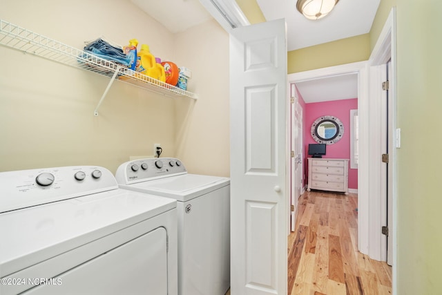 laundry area with washing machine and clothes dryer and light hardwood / wood-style floors