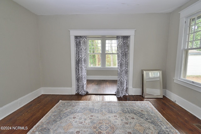 empty room with plenty of natural light and dark hardwood / wood-style flooring