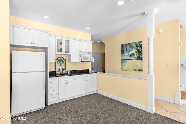 kitchen with sink, white appliances, light colored carpet, and white cabinetry